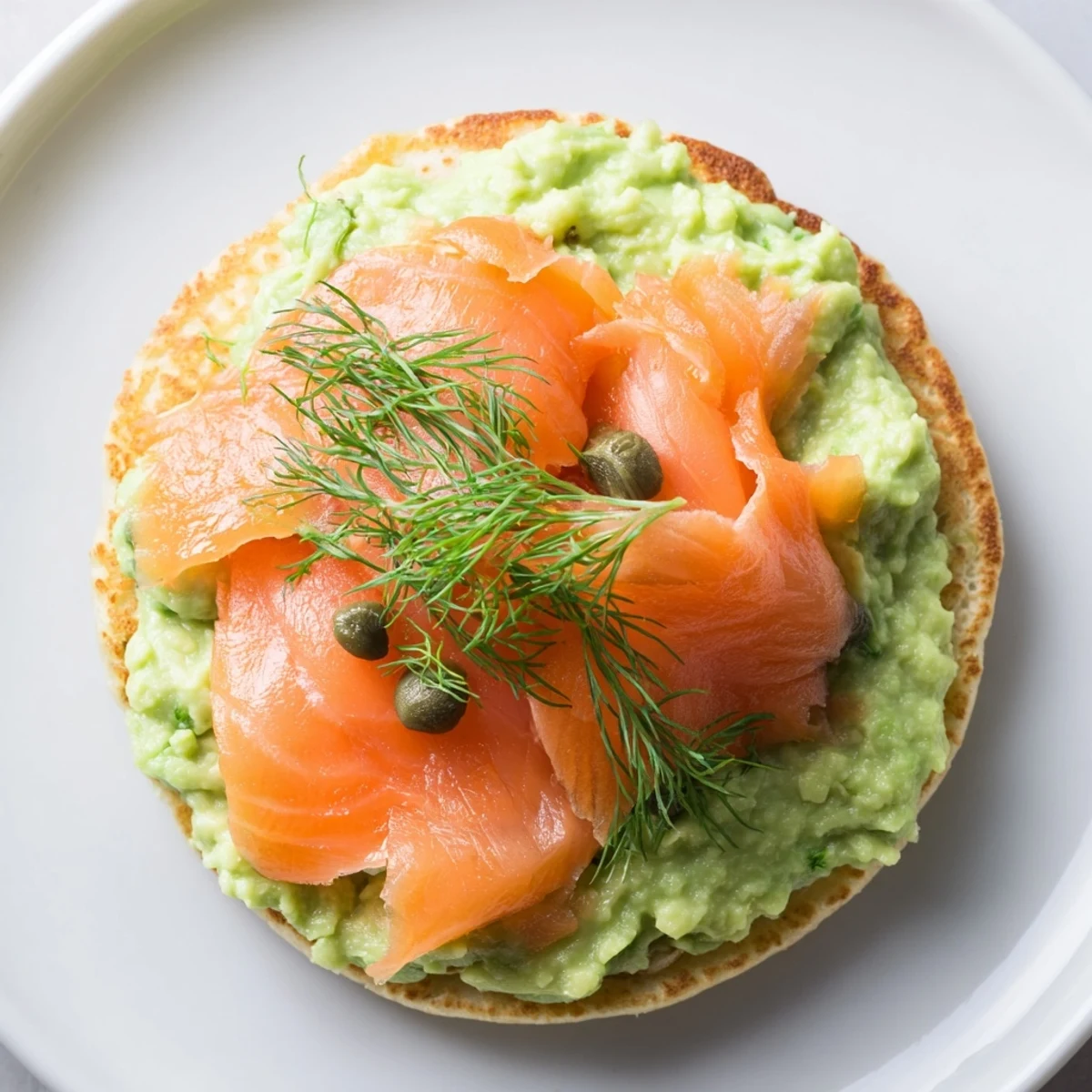 Golden, fluffy Quark Blinis topped with smoked salmon, creamy avocado spread, and fresh herbs, ready to serve.
