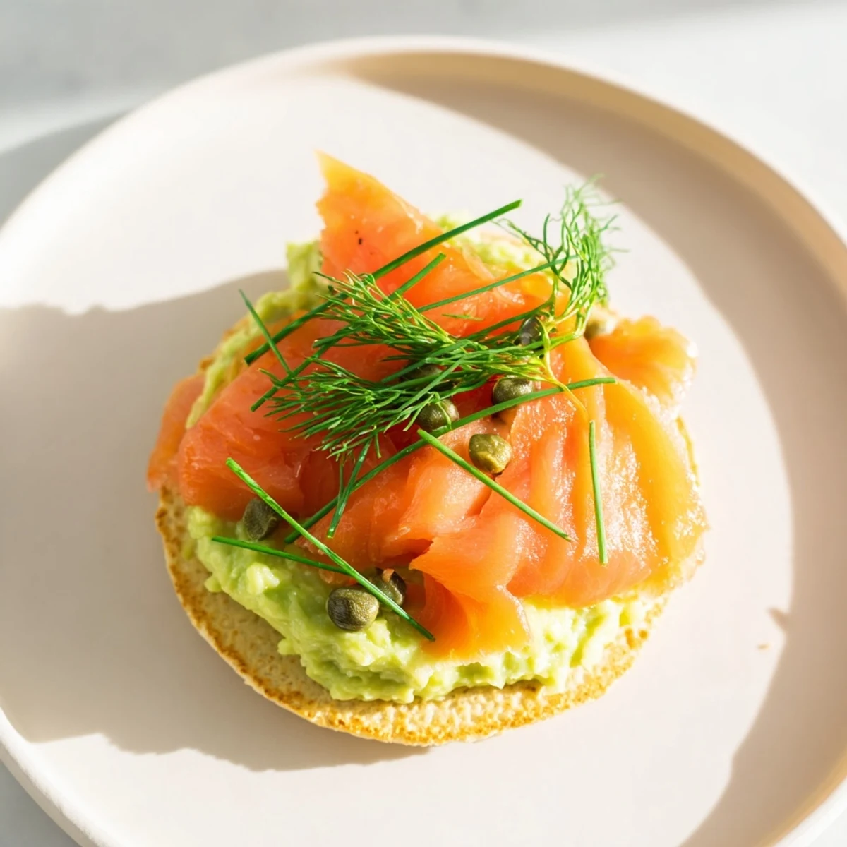 A plate of Quark Blinis: small, savory pancakes topped with smoked salmon and vibrant avocado cream.