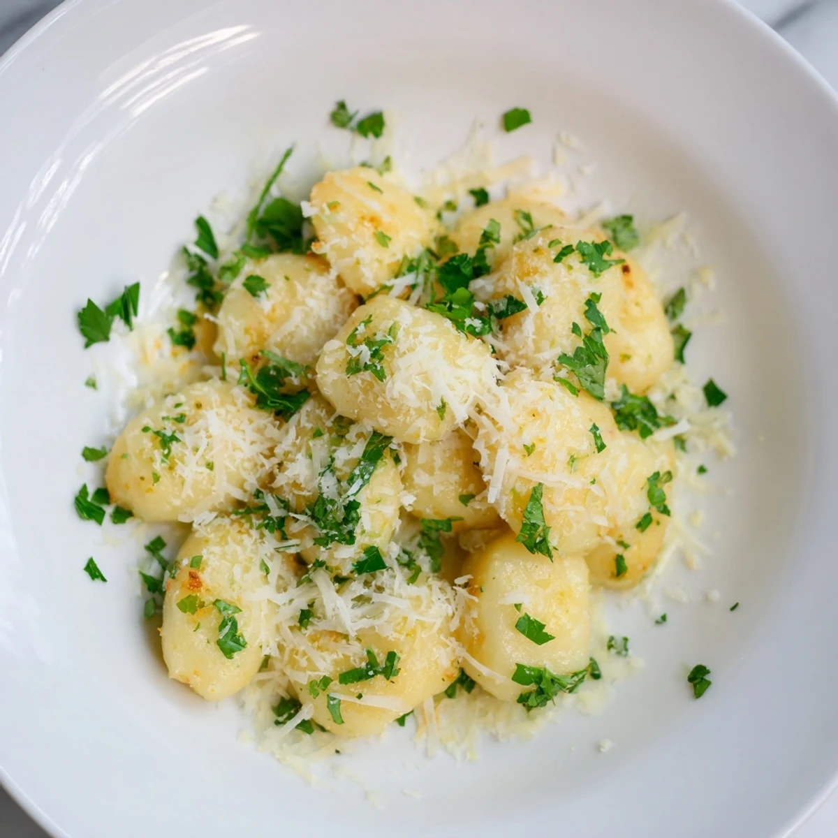 Golden-brown potato dumplings, swimming in a rich brown butter, with Parmesan and parsley garnish.