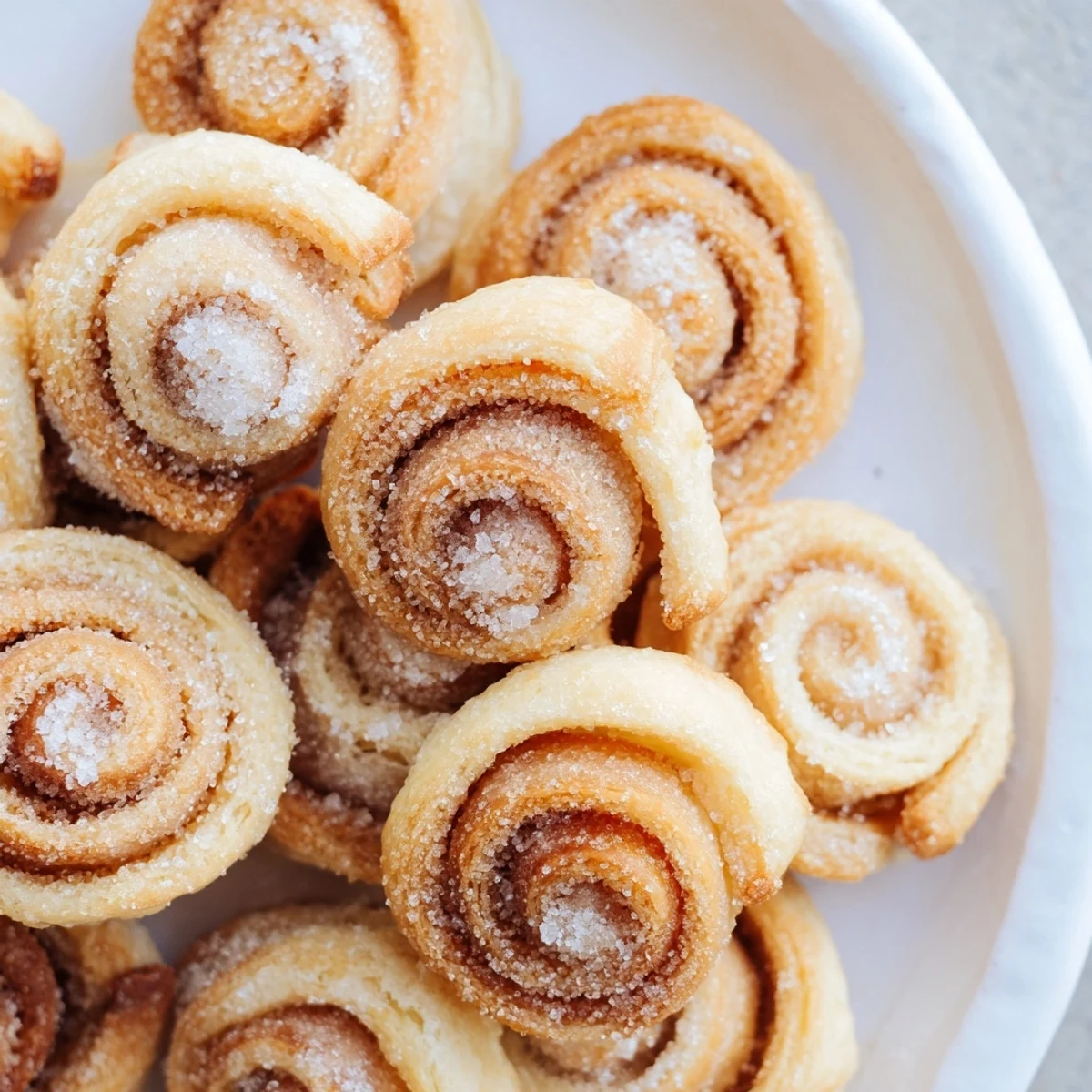 Close-up of fluffy air fryer Ensaimada Bites, showcasing their spiral shape and sugar dusting.