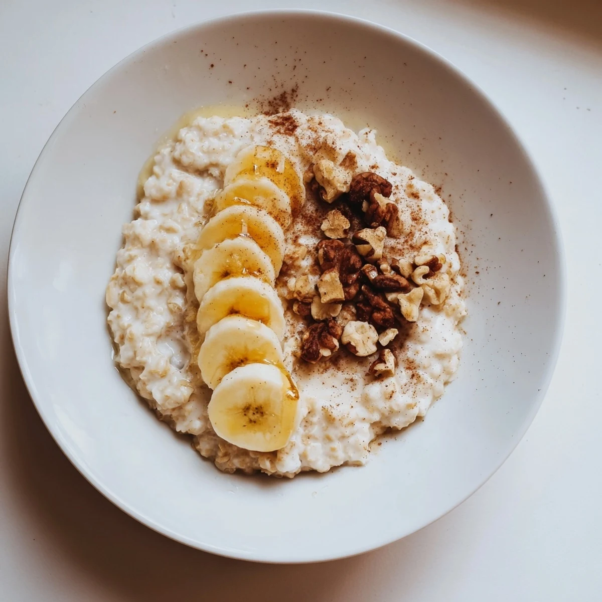 Close-up of a steaming bowl of microwave banana oats, with cinnamon and a drizzle of honey.