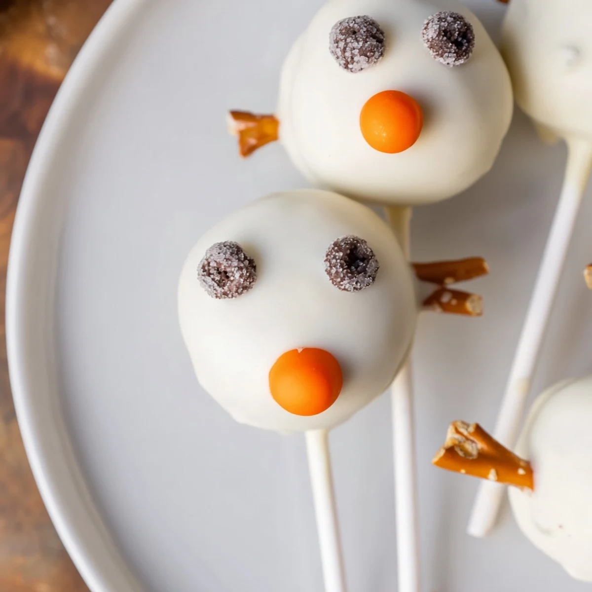 Oreo Snowman Cake Pops, coated in white chocolate, ready to be decorated with festive sprinkles and mini chocolate chips.