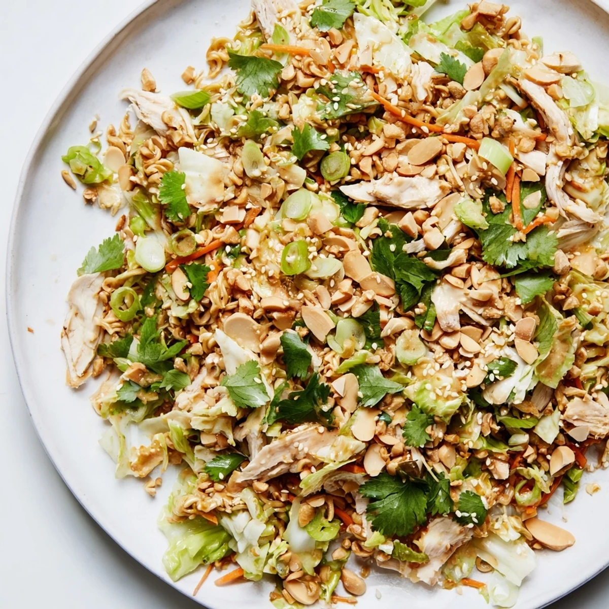 See a bowl, full of Crunchy Ramen Chicken Salad, with visible vegetables and toasted sesame seeds.