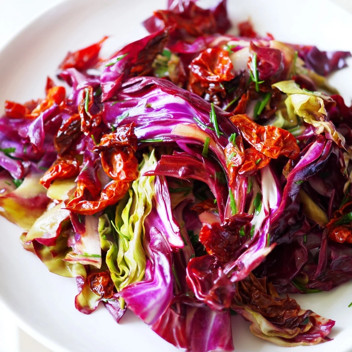 A colorful bowl of Cabbage Salad With Sundried Tomatoes, featuring crisp shredded cabbage mixed with vibrant red bell pepper and sweet sun-dried tomatoes.