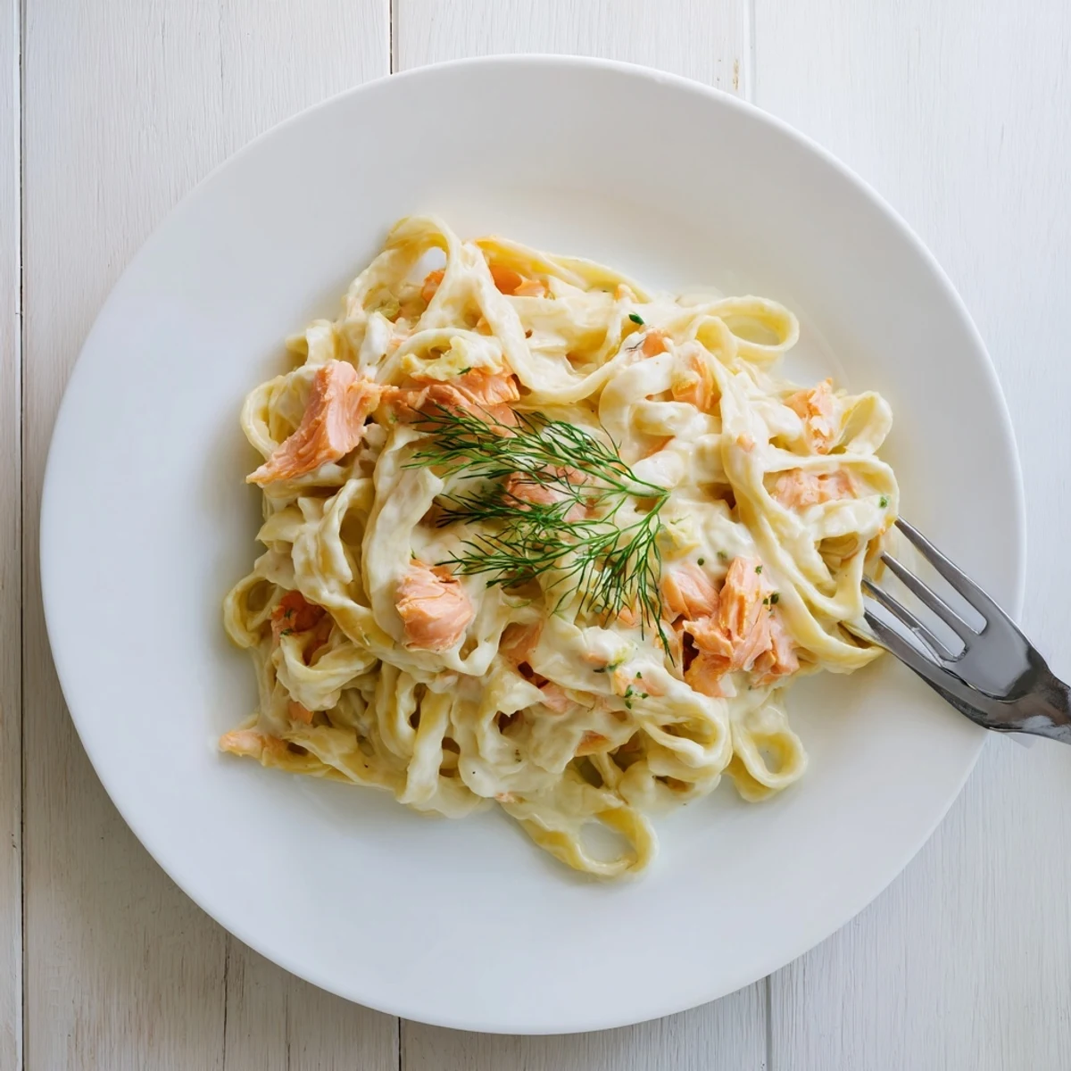 Salmón ahumado y pasta fettuccine en salsa cremosa, servida con hierbas frescas y limón.
