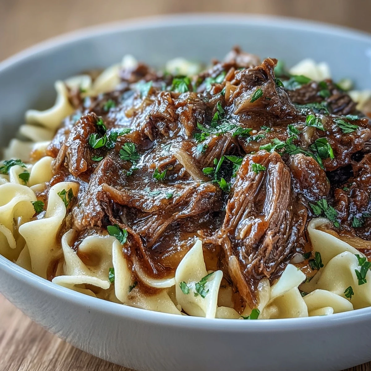 Crockpot French Onion Pot Roast Pasta: tender shredded beef and caramelized onions on buttery egg noodles.