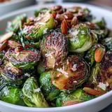 Plato de coles de Bruselas crujientes y aromáticas, realzadas con limón, hierbas frescas y almendras doradas.  