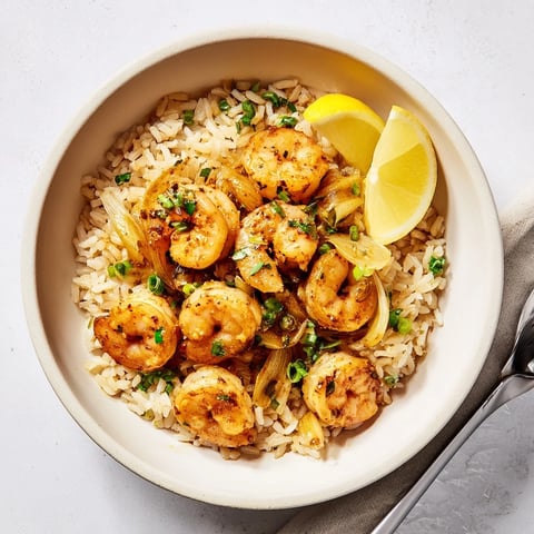 Tazón de arroz con camarones al ajo, resaltando los camarones jugosos y dorados.  