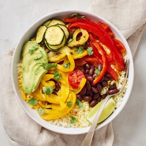 Tazones de arroz español soleados, vibrantes con vegetales asados y guarniciones frescas.  