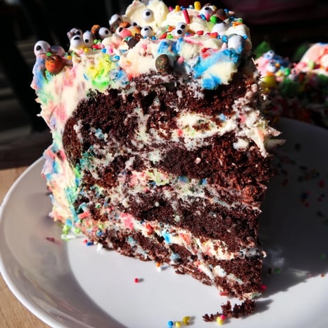 A slice of whimsical Chaotic Rat Cake, showcasing its disorganized, colorful frosting swirls.