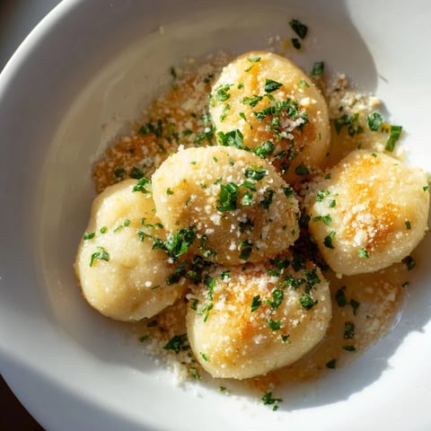 Tender potato dumplings glistening in a flavorful garlic-Parmesan brown butter sauce, ready to serve.