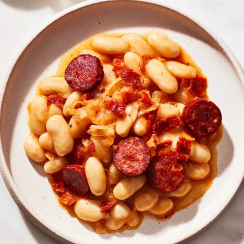 A steaming bowl of Fabada Asturiana, featuring savory chorizo and creamy white beans.