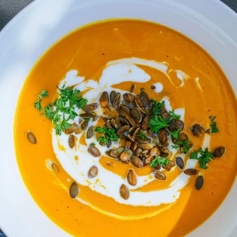 Creamy Pumpkin & Curry Soup, garnished with fresh herbs and toasted seeds, ready to savor.