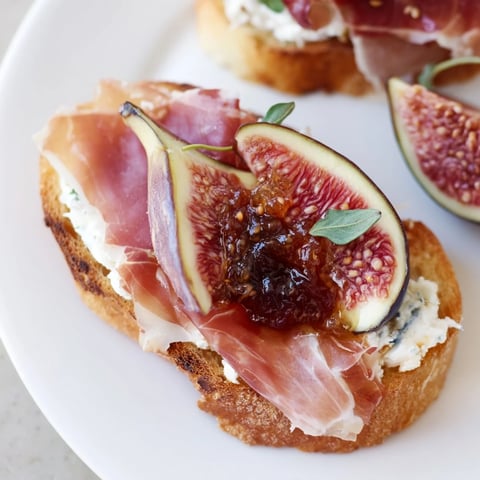 Glistening, delicate Jamón Ibérico topping a fresh, creamy crostini appetizer, ready to enjoy.
