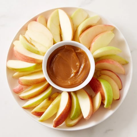 Crisp apple slices artfully arranged around a glistening caramel dip, perfect for dipping.