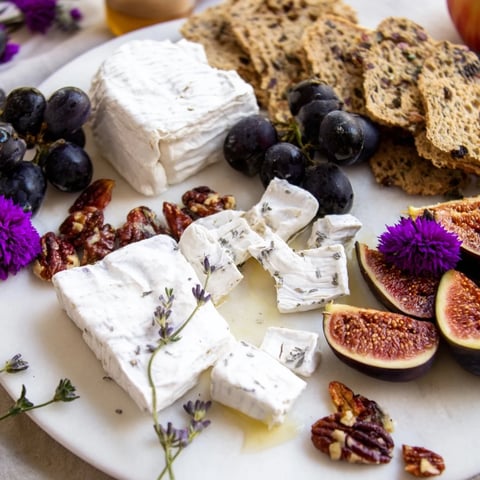 A beautifully arranged Lavender Haze cheese platter with goat cheese, brie, grapes, and figs perfect for entertaining.