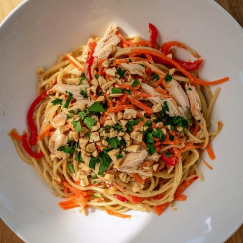 A bowl of chilled Thai-Inspired Peanut Chicken Pasta, bursting with colorful veggies and a creamy sauce.