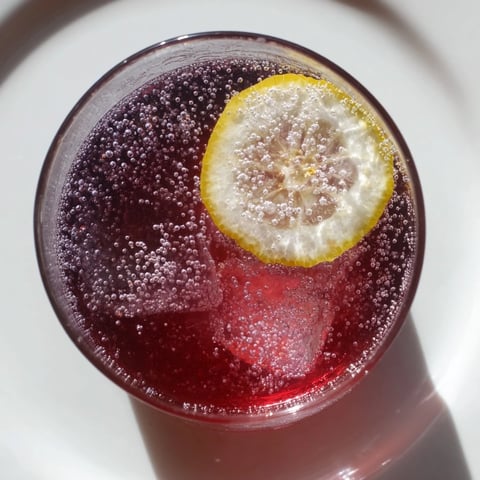 A tall glass of the Sleepy Girl Mocktail with a lemon garnish, a relaxing bedtime treat.