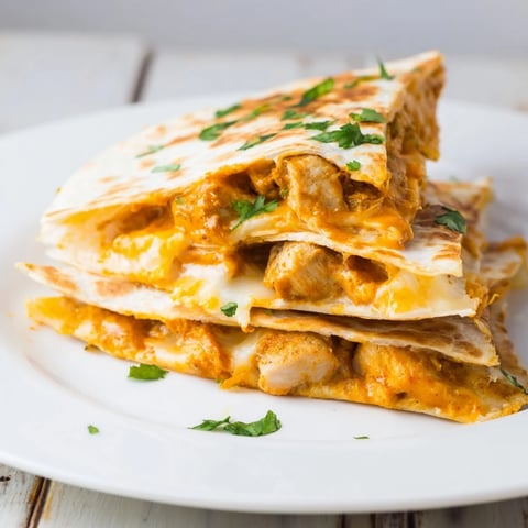 Delectable butter chicken quesadillas, warm, cheesy, and spiced, served with fresh cilantro and lime.