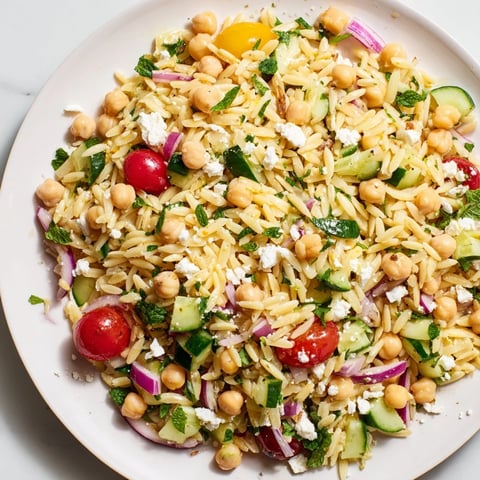 Bright, colorful Lemony Chickpea Orzo Salad, with chickpeas, herbs, and glistening dressing, ready to eat.