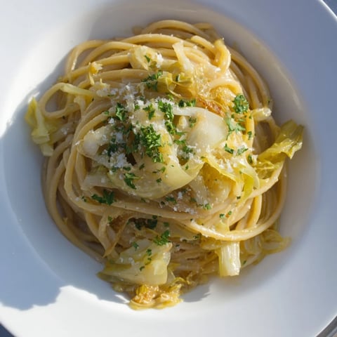 La pasta con repollo y ajo se sirve al dente, cubierta con Parmesano fundido y perejil fresco.