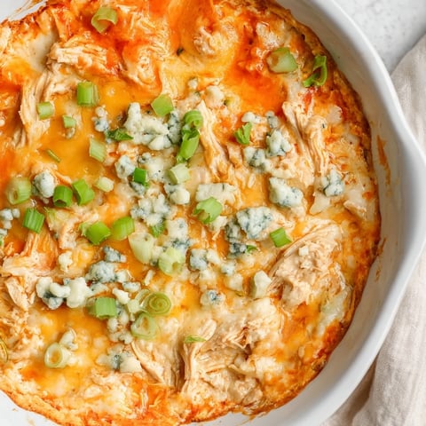 Un bol de queso Buffalo Chicken Dip humeante con cucharadas de chips de totopo listas para compartir.