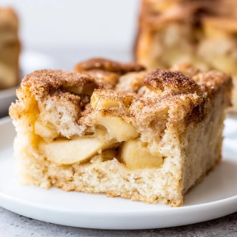 Baked Apple Cake in a rustic dish, warm slices topped with cinnamon sugar and tender apples.