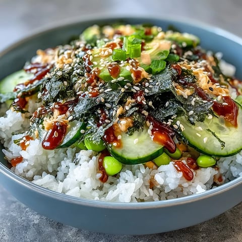 1. Vibrant seaweed snack sushi bowl with fluffy rice, crisp cucumber, creamy avocado, and savory nori strips, drizzled with spicy mayo.  