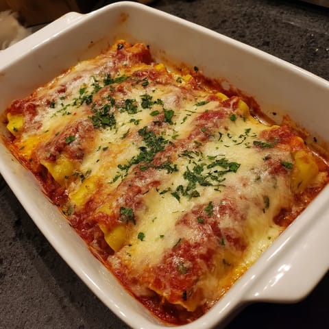 Un plato de canelones cremosos de carne y bechamel.