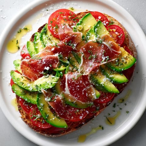 Una tostada mediterránea con tomate, aguacate y jamón serrano.