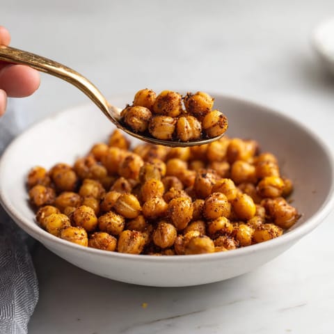 Una persona cocinando garbanzos crujientes al horno con especias.