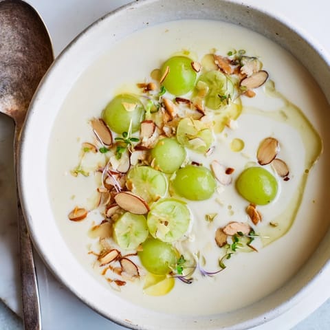 Delicado Ajo Blanco de Almendras, sopa fría española, adornada con almendras tostadas y aceite.