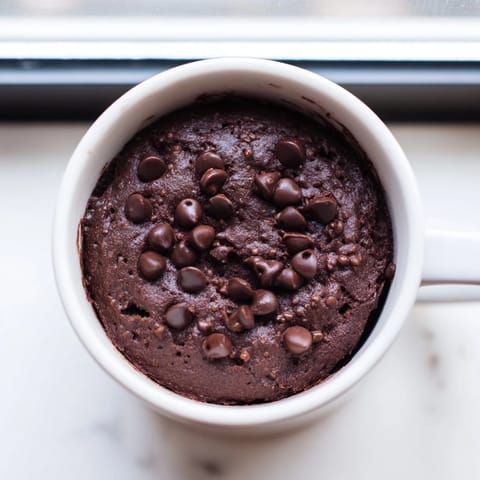 Steaming chocolate mug cake, a quick American dessert, topped with optional chocolate chips.