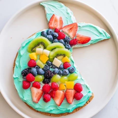A whimsical dessert, this Mermaid Tail Fruit Pizza shows colorful fruit artfully arranged.
