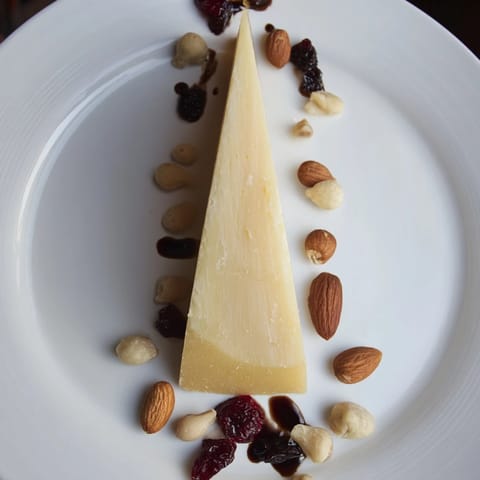 Delicious The Sundial cheese board appetizer showcasing a balsamic glaze "shadow" and varied gourmet nuts.