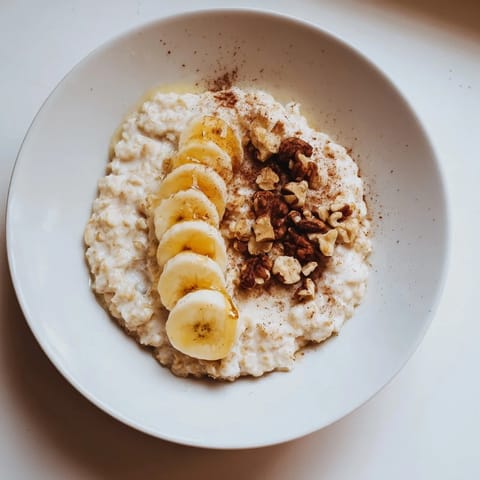 Close-up of a steaming bowl of microwave banana oats, with cinnamon and a drizzle of honey.