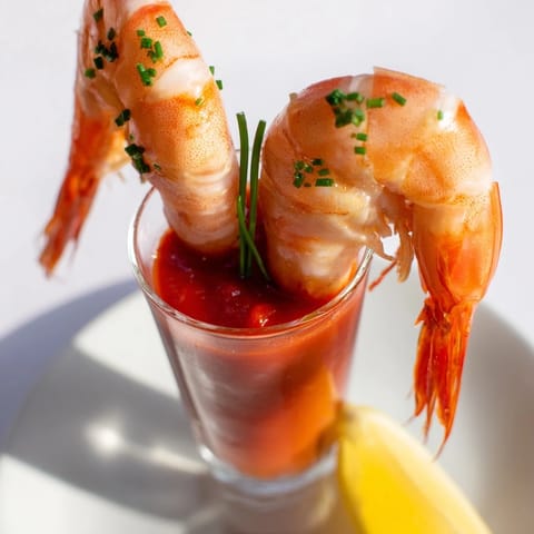 Retro Prawn Cocktail shooters overflowing with succulent shrimp and vibrant cocktail sauce, ready to serve.