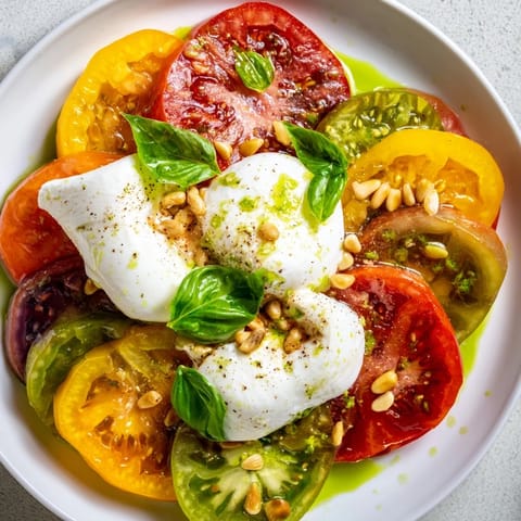 Vibrant heirloom tomato salad board featuring fresh burrata cheese drizzled with fragrant basil oil.