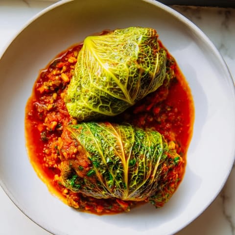 Golden vegan cabbage rolls topped with fresh parsley, nestled in a ceramic baking dish for a rustic feel.  