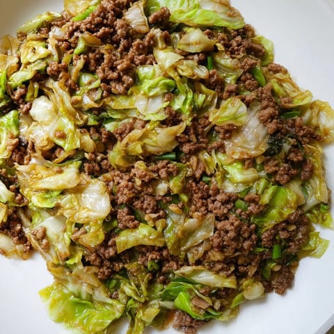 A vibrant bowl of Chinese Ground Beef and Cabbage Stir-Fry, garnished with green onions and sesame seeds, perfect for a low-carb weeknight dinner.  