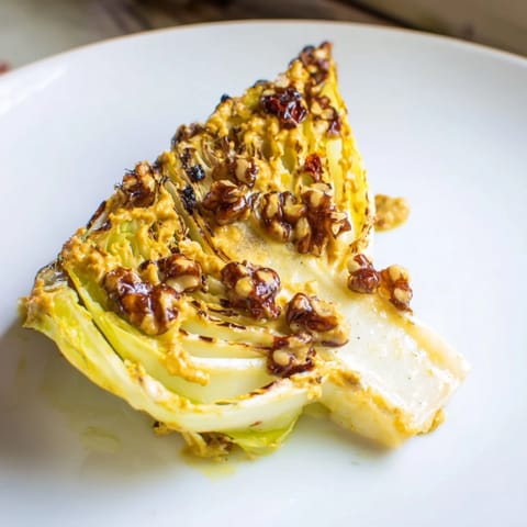 Crujientes gajos de col horneada sobre salsa romesco invernal con perejil y limón.