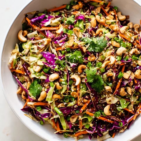 A refreshing Asian Cabbage Salad served in a white bowl with lime wedges and chopsticks.