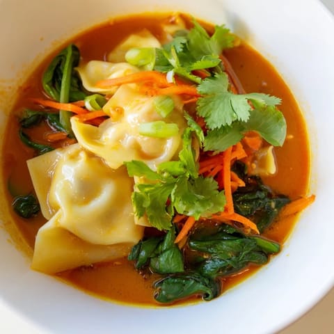 Listo en 25 minutos, este plato de fideos rellenos y coles en sopa tailandesa fusionada se sirve con cilantro.