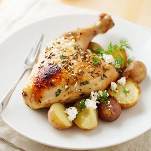 Roasted Chicken with Pot Potatoes, Lemon Herbs, and Feta on a rustic platter, garnished with lemon wedges.