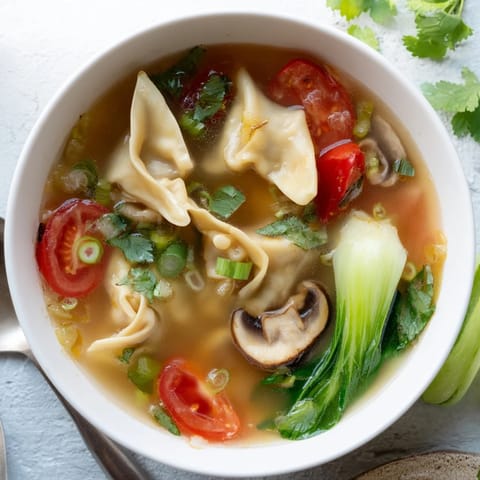Tom Yum Wonton Soup served hot with fresh cilantro, chili slices, and a zesty lime wedge garnish.