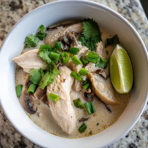 Un tazón humeante de Authentic Tom Kha Gai, con leche de coco cremosa, pollo tierno y setas flotantes.