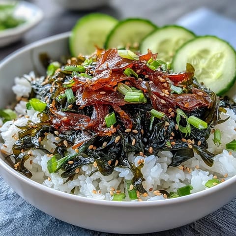 Bowl de arroz con nori y algas con wakame hidratado, cebollín picado y palitos de nori crujientes.
