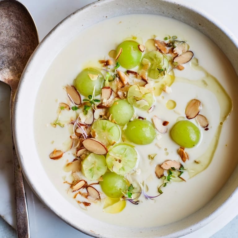 Delicado Ajo Blanco de Almendras, sopa fría española, adornada con almendras tostadas y aceite.