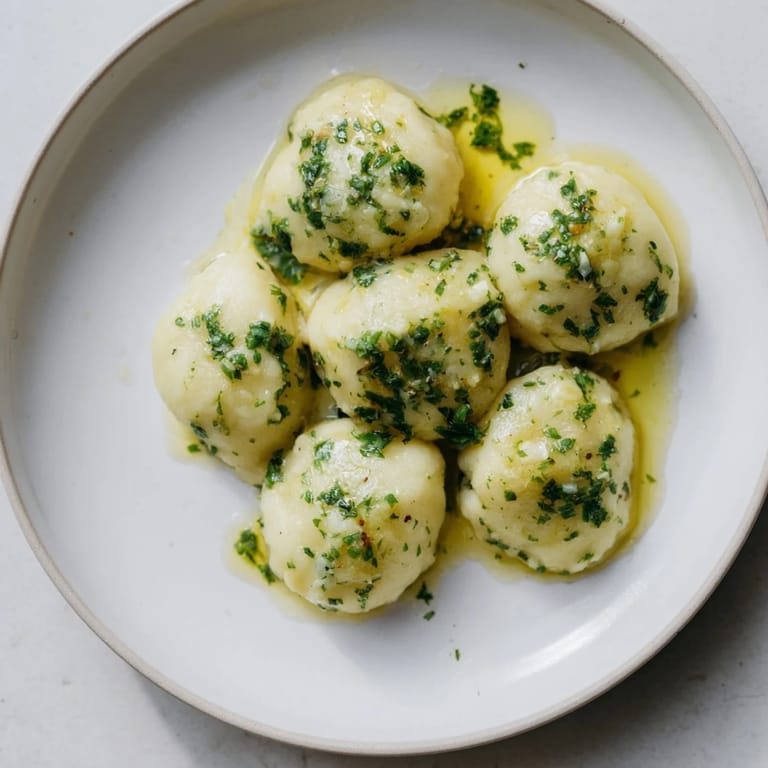 Steaming plate of comforting German potato dumplings, a vegetarian side dish enhanced with truffle oil.