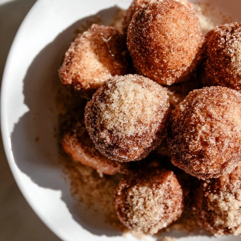 A close-up of delicious Air Fryer Cinnamon Donuts, lightly brushed with butter and covered in sweet cinnamon.